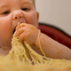 Baby eating spaghetti with hands